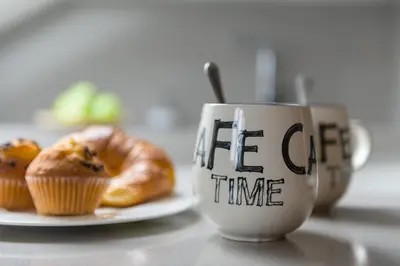 a coffee cup and a plate of muffins on a counter at Alojamiento Santa Maria in Milladoiro