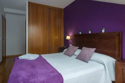 a bedroom with a large bed with purple walls at Alojamiento Santa Maria in Milladoiro