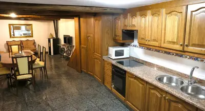 a kitchen with wooden cabinets and a sink and a microwave at A casa do pozo - AS CASAS DO POZO - in Folgoso