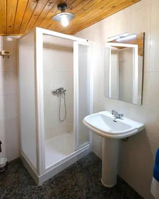 a white bathroom with a shower and a sink at A casa do pozo - AS CASAS DO POZO - in Folgoso