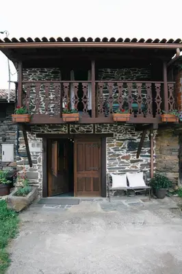 a building with a porch with two white benches at La Casita de Coelho in Doade