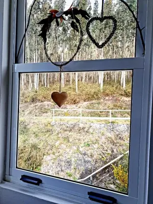 a window with a heart ornament hanging from it at Casa Natura Galicia in Santa María La Mayor del Rosario