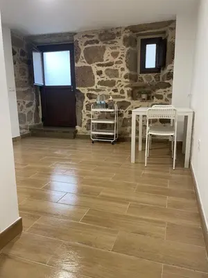 a room with a table and chairs and a stone wall at Arteleira2 Rooms in Padrón