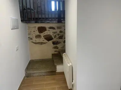 a hallway with a staircase with a stone wall at Arteleira2 Rooms in Padrón