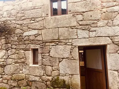 a stone building with a door and two windows at Arteleira2 Rooms in Padrón