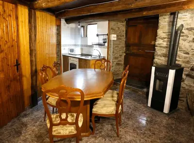 a kitchen with a wooden dining table and chairs at A casa dos carros - AS CASAS DO POZO - in Folgoso