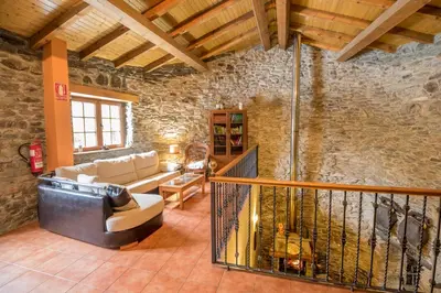 a living room with a couch and a stone wall at Casa Rural La Fuente in Tejedo del Sil
