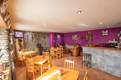 a restaurant with purple walls and wooden tables and chairs at Casa Rural La Fuente in Tejedo del Sil