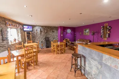 a living room with purple walls and wooden tables and chairs at Casa Rural La Fuente in Tejedo del Sil
