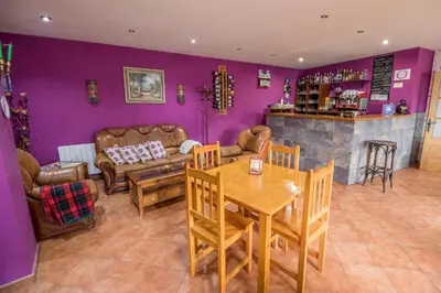 a living room with purple walls and a table and chairs at Casa Rural La Fuente in Tejedo del Sil