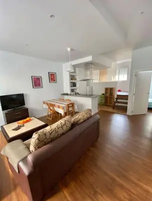a living room with a brown couch and a kitchen at PRAD in Foz