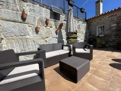 an umbrella and chairs on a patio with a stone wall at YourHouse A Casa Da Corona casa rural in Parada del Monte