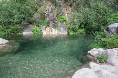 a pool of clear water in a river with rocks at YourHouse A Casa Da Corona casa rural in Parada del Monte