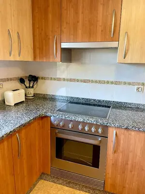 a kitchen with wooden cabinets and a stove top oven at Casa rural Herminia in Ourense