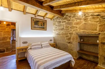 a bedroom with a bed and a stone wall at Casa pepe in Nogueira de Ramuin