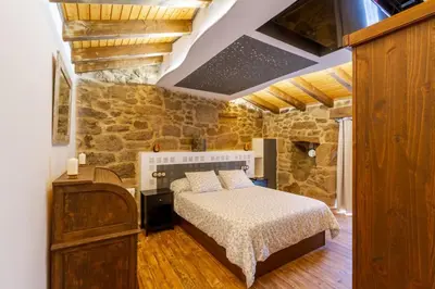 a bedroom with a bed and a stone wall at Casa pepe in Nogueira de Ramuin