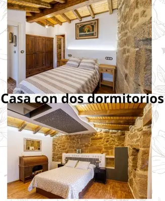 a bedroom with two beds and a stone wall at Casa pepe in Nogueira de Ramuin