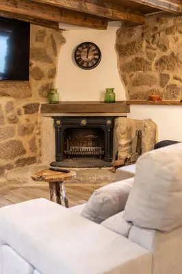a living room with a stone fireplace with a clock at Casa pepe in Nogueira de Ramuin