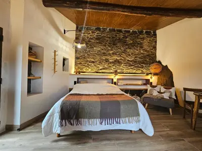 a bedroom with a bed and a stone wall at Viña Candaz By Oktheway in Taboada