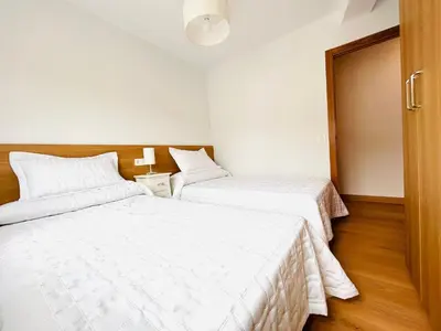 two beds in a room with white sheets at Apartamento San José in Milladoiro