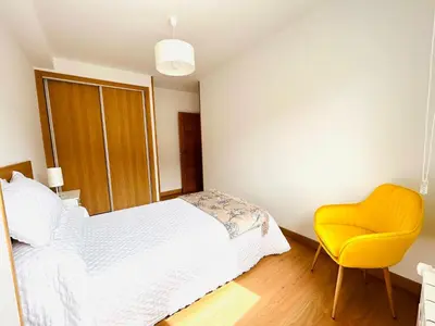a bedroom with a bed and a yellow chair at Apartamento San José in Milladoiro