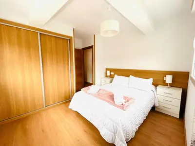 a bedroom with a large white bed and wooden cabinets at Apartamento San José in Milladoiro