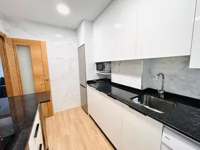 a kitchen with white cabinets and a sink at Apartamento San José in Milladoiro