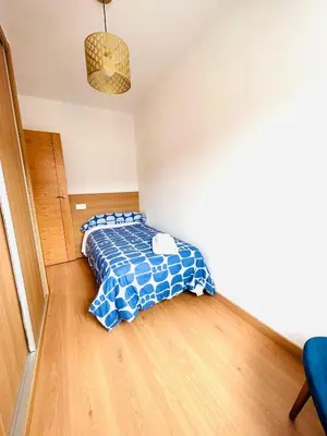 a bedroom with a bed with a blue comforter at Apartamento San José in Milladoiro