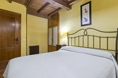 a bedroom with a white bed and a wooden door at Apartamentos rurales Casa Xepo in Rengos