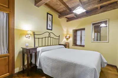 a bedroom with a white bed and a wooden ceiling at Apartamentos rurales Casa Xepo in Rengos