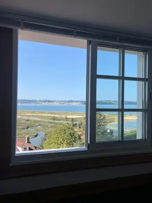 a window in a room with a view of the ocean at El Pedregal - Playa de Miño in Miño