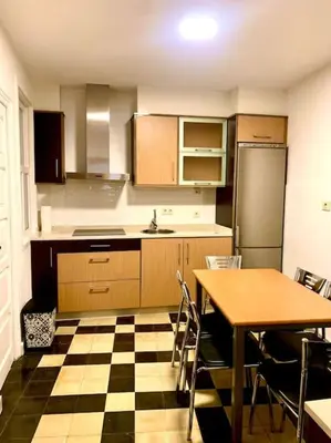 a kitchen with a checkered floor and a table and refrigerator at casa ribeiro in Ribadavia