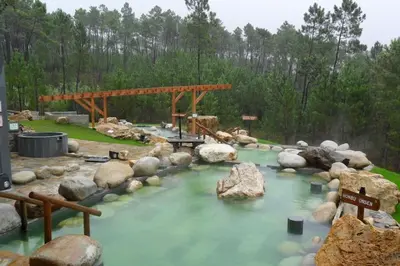 a pool of water with rocks and a wooden bridge at casa ribeiro in Ribadavia