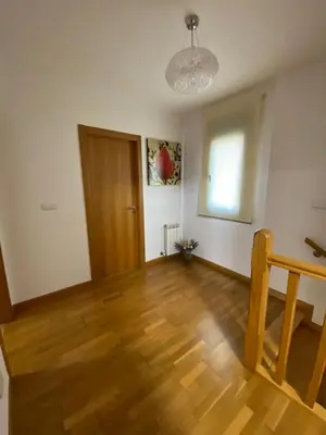 an empty living room with a wooden floor and a door at Casa do Aloumiño in Portomarin