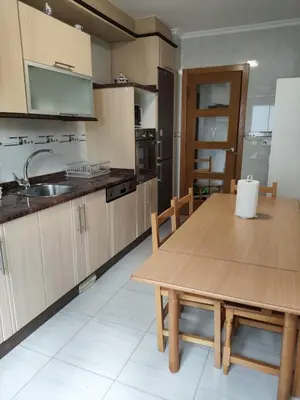 a kitchen with a wooden table and a sink and a counter at Casa do Aloumiño in Portomarin