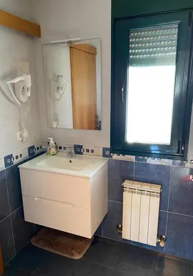 a bathroom with a white sink and a mirror at Casa do Aloumiño in Portomarin