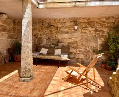 a stone room with a bench and a chair at Casa María da Reza in Ribadavia