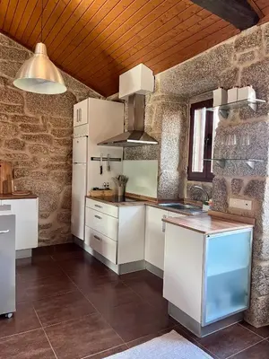 a kitchen with white appliances and a brick wall at Casa María da Reza in Ribadavia