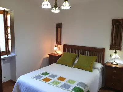 a bedroom with a bed with two night stands and two lamps at Habitaciones - La Pumarada de Limés I in Cangas del Narcea