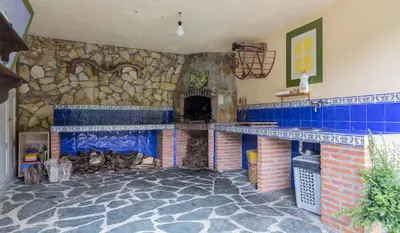 a living room with a stone fireplace with blue tiles at Habitaciones - La Pumarada de Limés I in Cangas del Narcea