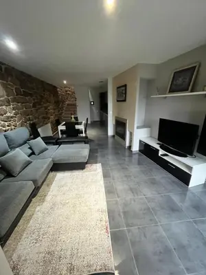 a living room with couches and a stone wall at A MIÑA CASIÑA -TERMAS OURENSE in Ourense