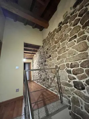 a stone wall in a room with a staircase at A MIÑA CASIÑA -TERMAS OURENSE in Ourense