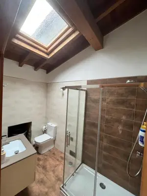 a bathroom with a shower and a toilet and a skylight at A MIÑA CASIÑA -TERMAS OURENSE in Ourense