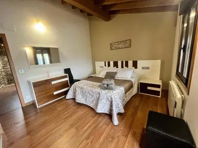 a bedroom with a bed and a wooden floor at A MIÑA CASIÑA -TERMAS OURENSE in Ourense