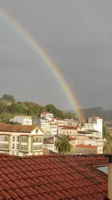 a rainbow over the roofs of a city at Apartamento Arcoiris in Betanzos