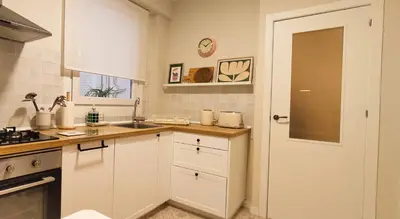 a kitchen with white cabinets and a white door at Apartamento Arcoiris in Betanzos