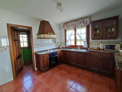 a kitchen with wooden cabinets and a tile floor at Casa de campo en Ribadeo in Ribadeo