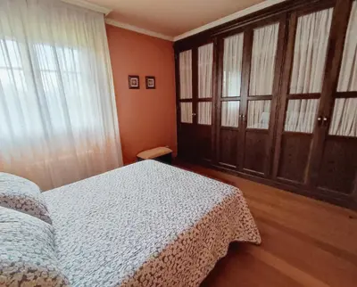 a bedroom with a bed and wooden floors and windows at Casa de campo en Ribadeo in Ribadeo