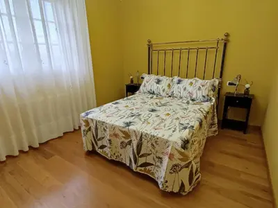 a bedroom with a bed with a blanket and a window at Casa de campo en Ribadeo in Ribadeo