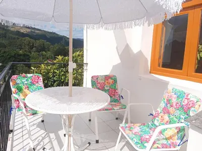 a table and chairs with an umbrella on a balcony at Casa Calvo in Vivero